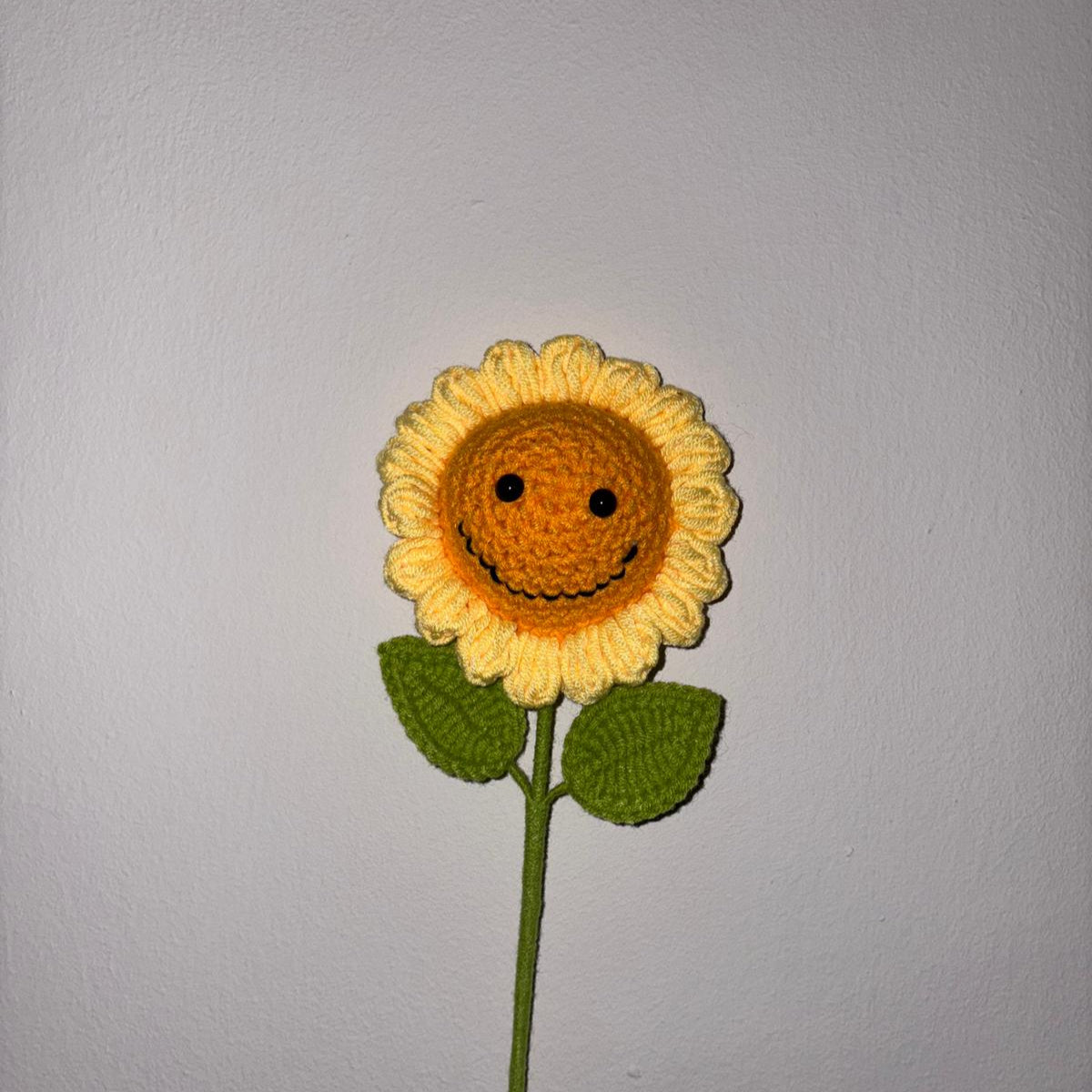 Crocheted sunflower with a face on a gray background
