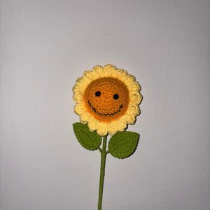 Crocheted sunflower with a face on a gray background