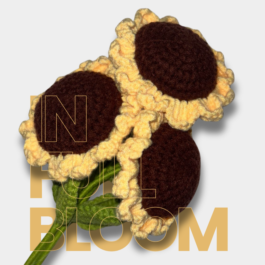 Crocheted sunflower with text 'IN FULL BLOOM' on a light gray background